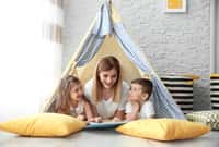 Nanny and little children reading book in