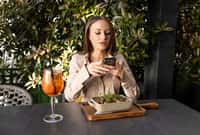 Woman browsing her phone during a meal