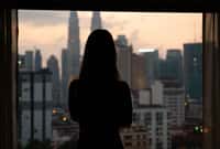 Silhouette of woman at sunset with city