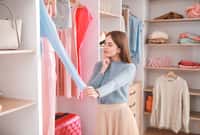 Beautiful young woman choosing clothes from large