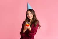 Happy young woman in party hat holding