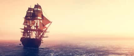 Pirate ship sailing on the ocean at sunset. Vintage cruise