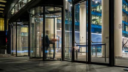 the flow of people passing through the revolving door of the modern office building at the end of the working day