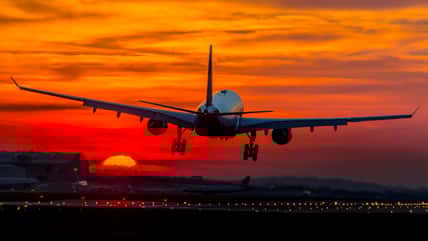 plane taking off on a runway into the sunset