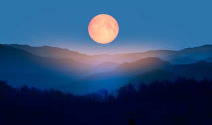 Beautiful landscape with blue misty silhouettes of mountains against super blue moon "Elements of this image furnished by NASA"