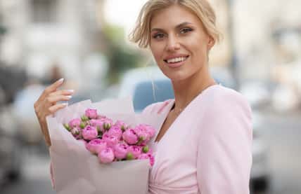 Happy woman holding flowers outdoor.