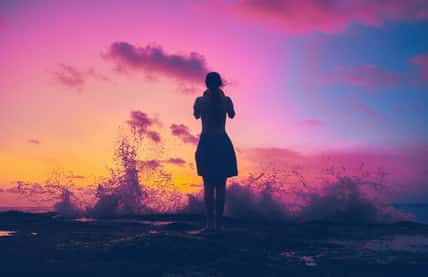 Silhouette of a girl on the shores of the Indian Ocean during a saturated sunset