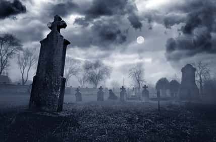 Old creepy graveyard on stormy winter day in black and white.
