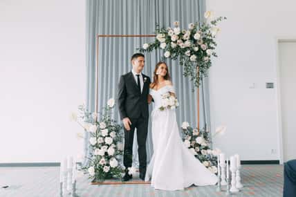 Stylish European wedding ceremony. The bride and groom are surrounded by guests. Arch and decor of fresh flowers.