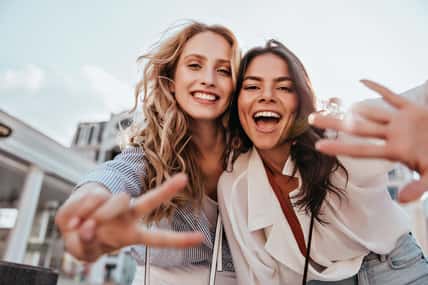 Lovable caucasian girls expressing positive emotions to camera. Outdoor photo of refined sisters posing on sky background.