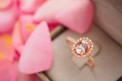 elegant wedding diamond ring in jewelry box on beautiful pink rose petal background close up