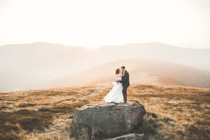 Happy wedding couple posing over beautiful landscape in the mountains.
