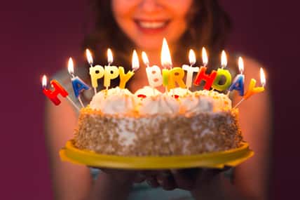 Hands of young woman holding birthday cake