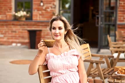 Beautiful woman drinking coffee in a cafe and eating croissant.