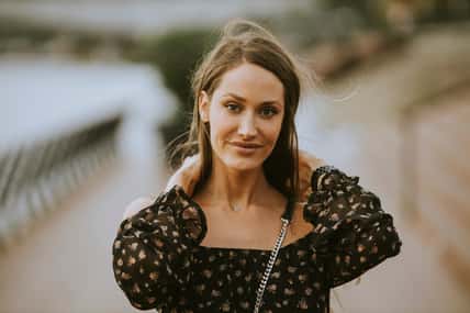 Pretty young long hair brunette woman walking on the riverside