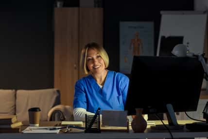 Female nurse working evening shift at table in clinic