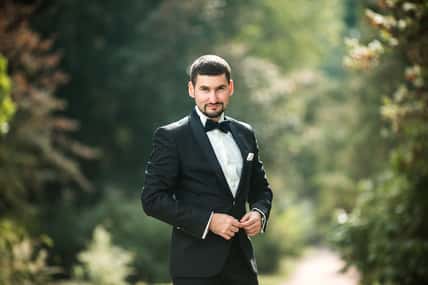 confident groom posing for the camera in the park