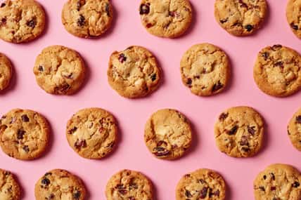 Fresh cookies with cranberries and white chocolate pattern on pink background