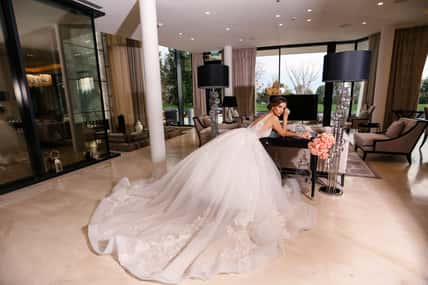 fashion interior photo of beautiful bride with dark hair in elegant wedding dress posing in luxurious interior