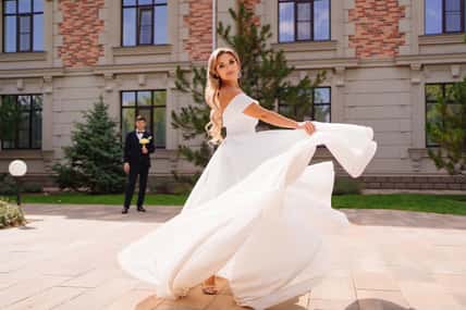 beautiful blonde bride dancing and whirling in front of the groom. the concept of wedding fashion and choosing a place for the celebration.