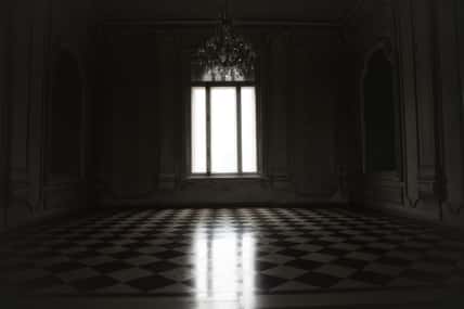 Window lit with mysterious white light in a spooky room built in baroque style.