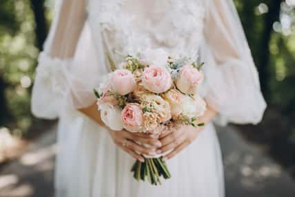 bride in a white wedding dress holding a bouquet of roses, peonies and greenery