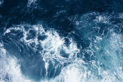 Top view on blue ocean waves and foam.