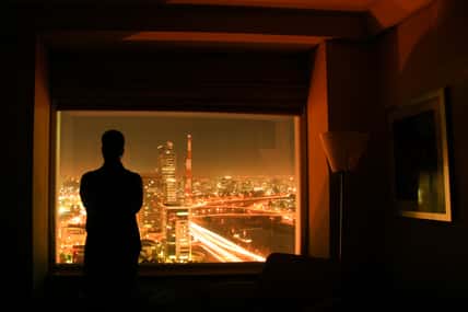 Silhouete of a person against the night landscape of the city of Sao Paulo, in a hotel room, in Brazil