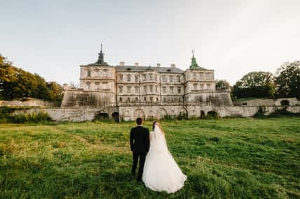 Newlyweds are walking their backs to the vintage Castle, renaissance palace for the wedding ceremony. Photo shoot near Medieval Castle.