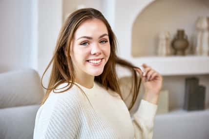Portrait of smiling european young woman on sofa in living room.