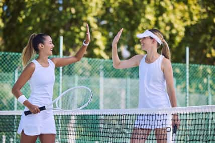 Tennis match winner and fit female athlete high five hands to success, celebrating after game on outdoor sports court. Women training exercise for wellness, healthy fitness lifestyle and summer fun