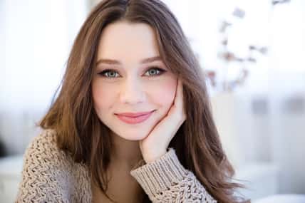 Portrait of beautiful happy young woman with long hair in the room