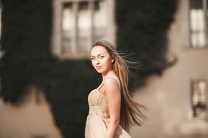 Beautiful girl with long hair posing in old castle with columns. Krakow Vavel.