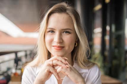 Portrait of beautiful young blonde woman drinking a cup of tea in balcony cafeteria. Happy smiling female relaxing in a coffee shop