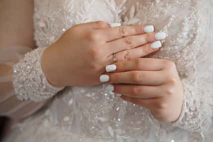 Close-up shot of a bride's hands displaying a delicate diamond engagement ring, symbolizing love, commitment and a joyous wedding moment