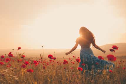 Young beautiful woman in spring field. concept of freedom. walking in amazing poppy field. Warm sunset colors. Soft colors.