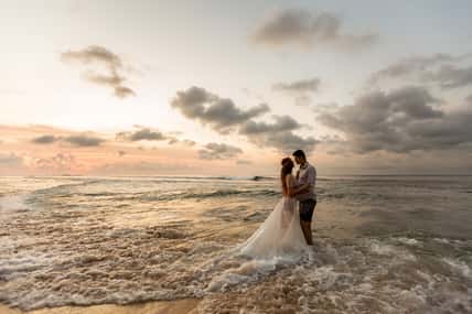 Bride and groom hugging on the beach standing in the sea water