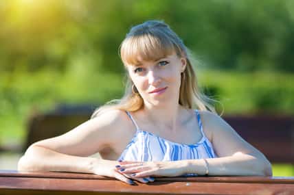 Portrait of a woman of Caucasian nationality on a summer sunny day in the park against the backdrop of greenery.