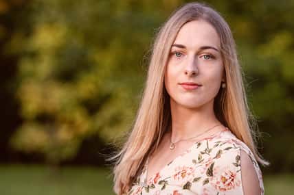 Portrait of a young blonde woman against a defocused landscape. Autumn color shade - image
