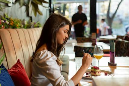 Beautiful young woman eating fruit cake alone at the restaurant