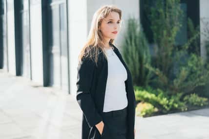 a cute blonde in a business black suit walks around the territory of a business center