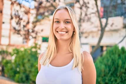 Young blonde girl smiling happy walking at the park.