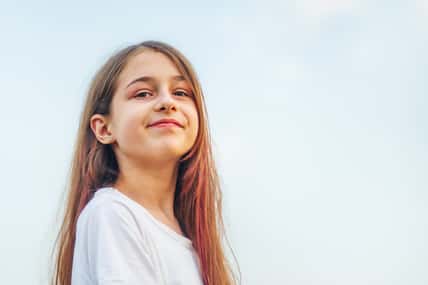 Girl 11 years old. Portrait of a teenage girl with long hair against the sky.