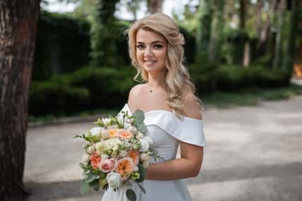 Smiling wedding couple in love in the forest hold hands and hug. Sunny day, good mood. Portrait of a beautiful blonde.