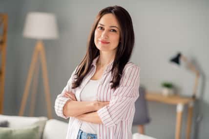 Photo of successful lovely girl folded arms posing calm domestic atmosphere spacious apartment inside.