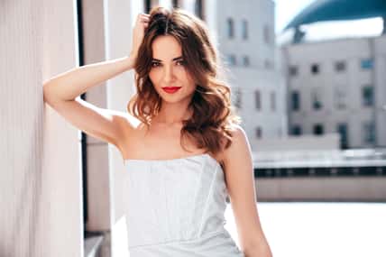 Young beautiful brunette female in trendy evening silver dress.