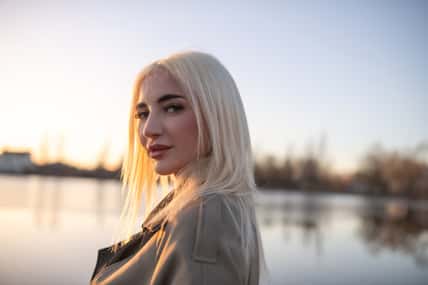 Portrait of a young beautiful blonde girl in a dress by the river.