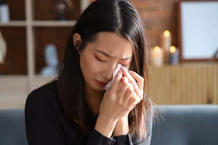 Grieving young Asian woman crying at funeral, closeup