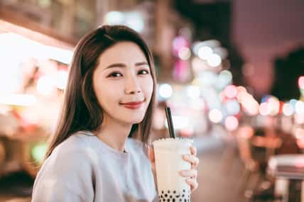 Asian woman enjoy bubble milk tea with street food in Night Market