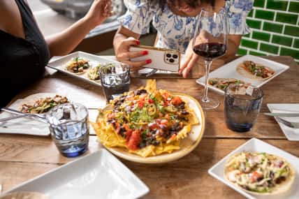 Close-up of woman photographing Mexican food at restaurant table